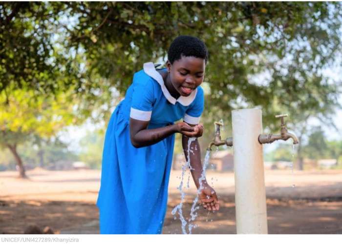 girl drinking water from pump in Malawi