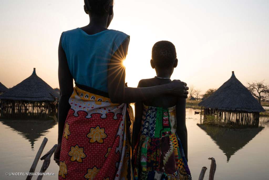A mother and daughter look out over submerged houses in Panyagor in Twic East, Jonglei State in South Sudan.   Flooding has devastated much of the area and it is estimated that more than 800,000 people in South Sudan have been affected by the current flooding.  Contrary to previous years, water levels in many locations are not receding despite the onset of the dry season.  This year, a higher number of children are now exposed for longer periods of time to the risks and vulnerabilities associated with the impact of floods.  Many have had to flee their destroyed homes and are unable to find food as fields have also been flooded.  More than 390,000 children are now without access to basic services including social services, clean water, proper healthcare and schooling. Local authorities estimate that as much as 85% of Twic East is affected by flooding with as many as 80,000 people having fled the area for safer drier ground. Climate change is impacting children in South Sudan as never before. South Sudan is ranked number 7 worldwide in children’s exposure to climate change and environmental shocks. Young people living in South Sudan are among those most at risk of the impacts of climate change, threatening their health, education, and protection, according to a recent global UNICEF Report. Climate change has contributed to increased severity, durations and spread of annual floods in South Sudan, which are increasingly unpredictable. Since 2019, floods have affected between 750,000 and one million people every year, forcing half of them to leave their homeland in search of safety. UNICEF and partners are responding to the immediate needs of people affected and displaced by floods, providing them with essential supplies, including soap, drugs and education materials, while ensuring continuation of lifesaving services such as healthcare, vaccination, nutrition and access to water, sanitation and hygiene (WASH). To reduce the impact of floods on the most vulne